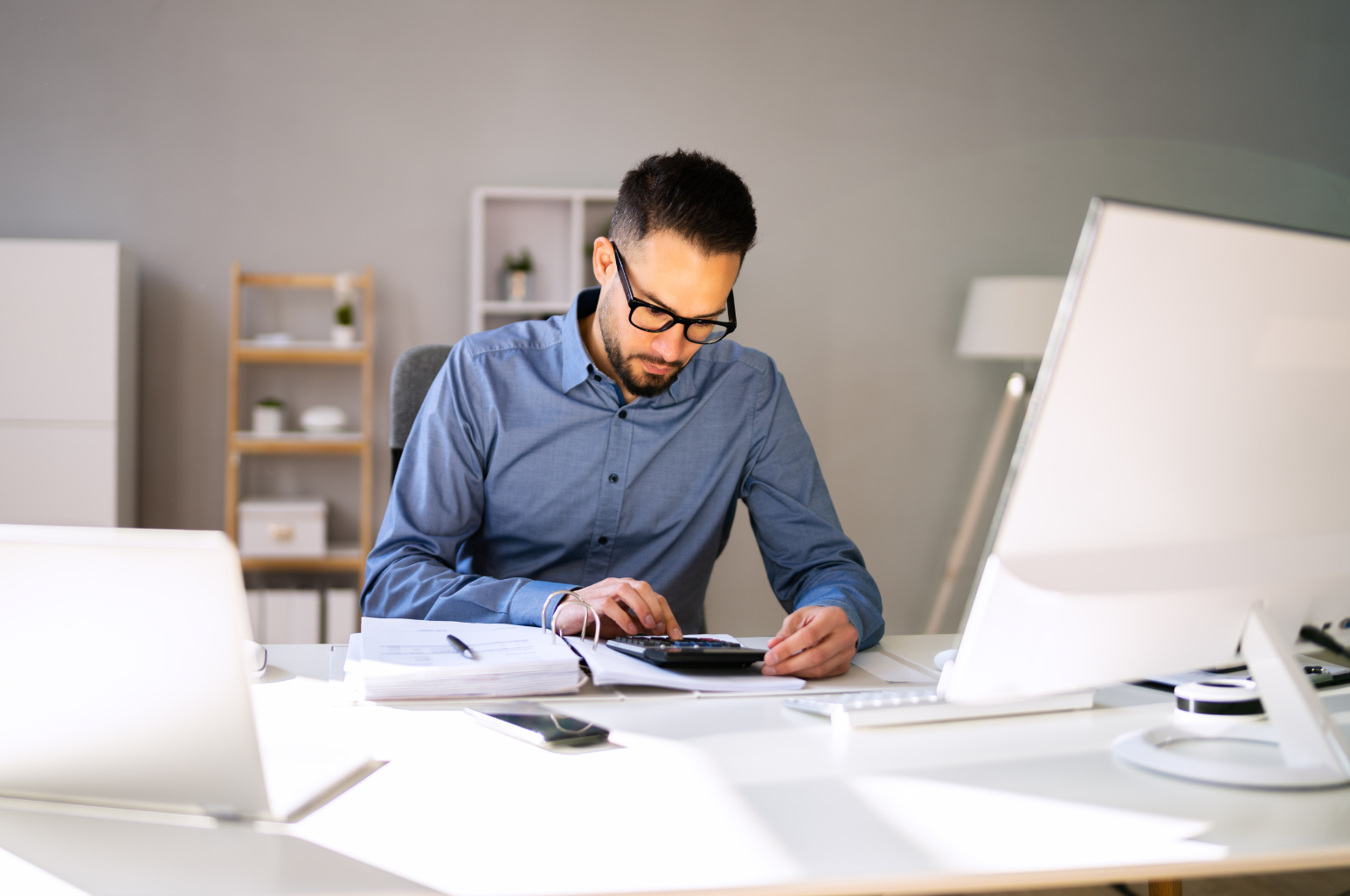 man sitting at desk typing on a calculator